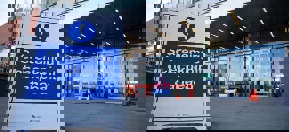 Floor-standing displays indicates "Screening Checkpoint ahead" in front of the entrance of a business building.