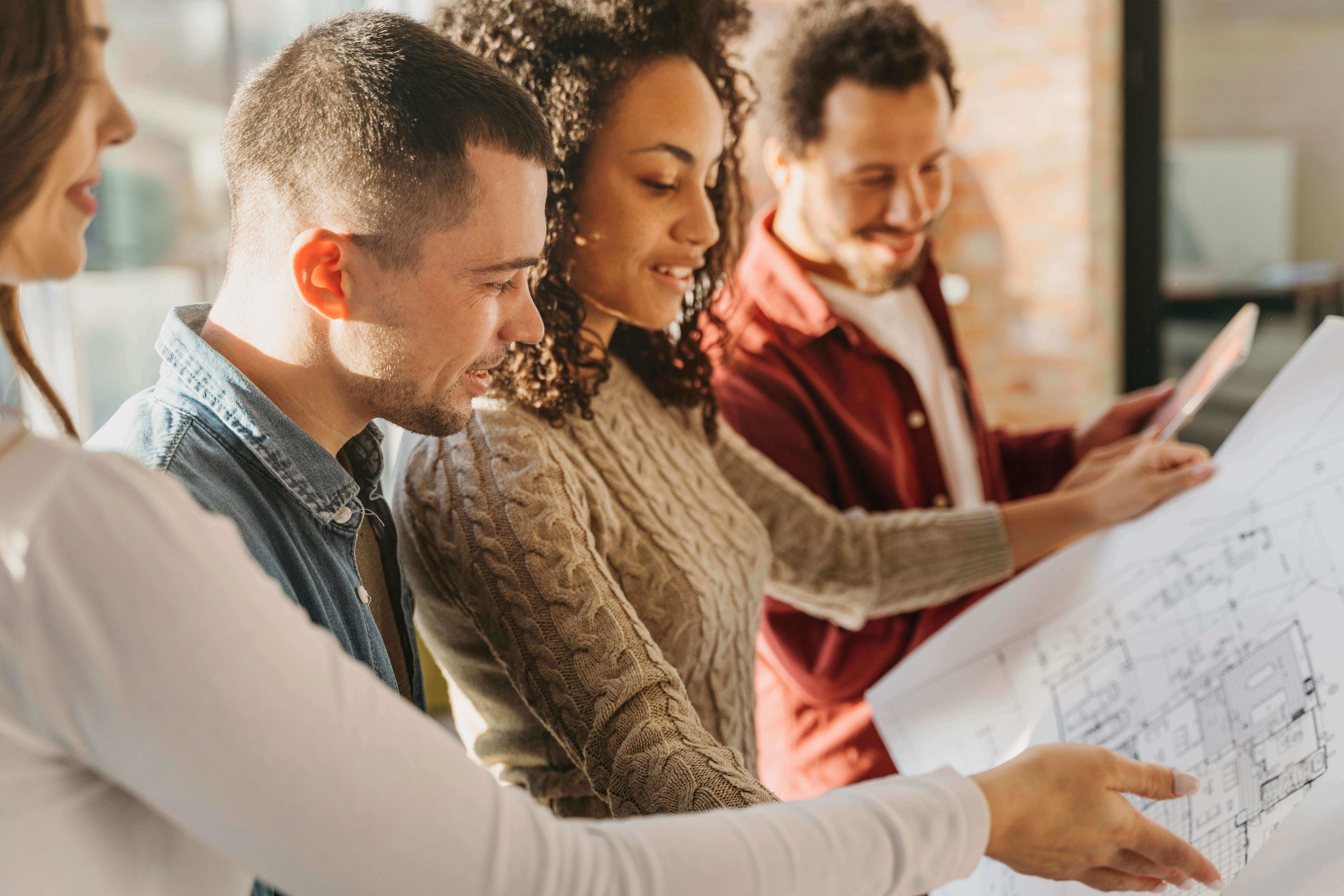 A group of people looking at a blueprint or a plan. They are smiling.