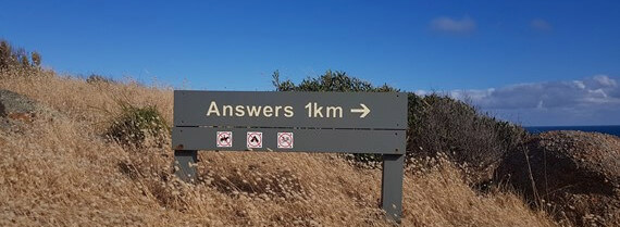 Grassy hillside with a sign showing an arrow pointing from left to right and words answers 1km