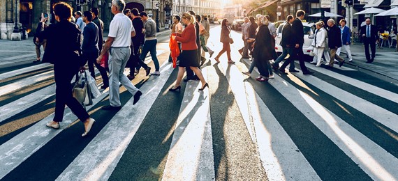 People crossing street on zebra in a city.