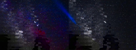 Person shining light at the night sky full of stars