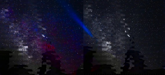 Person shining light at the night sky full of stars