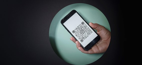 A hand holding cellphone. There is a QR code on the screen.